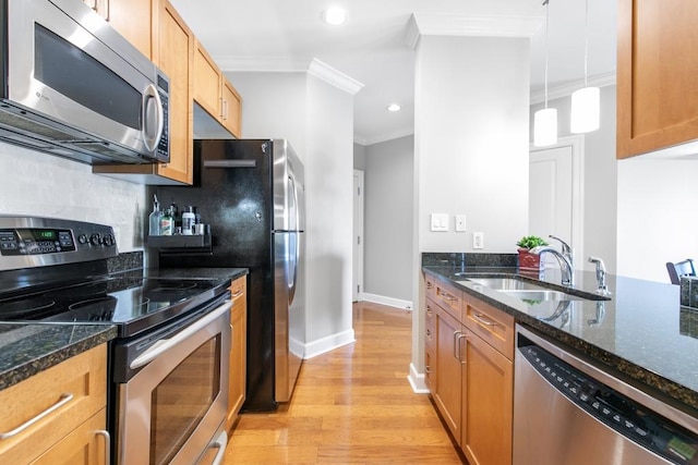 kitchen featuring stainless steel appliances, ornamental molding, dark stone counters, and decorative light fixtures