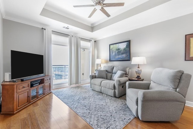 living room with crown molding, ceiling fan, a tray ceiling, and light hardwood / wood-style floors