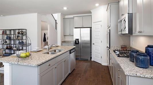 kitchen featuring light stone countertops, stainless steel appliances, sink, dark hardwood / wood-style floors, and an island with sink