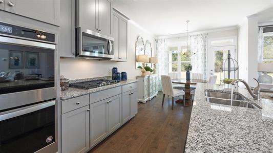 kitchen featuring pendant lighting, sink, dark hardwood / wood-style floors, light stone counters, and stainless steel appliances