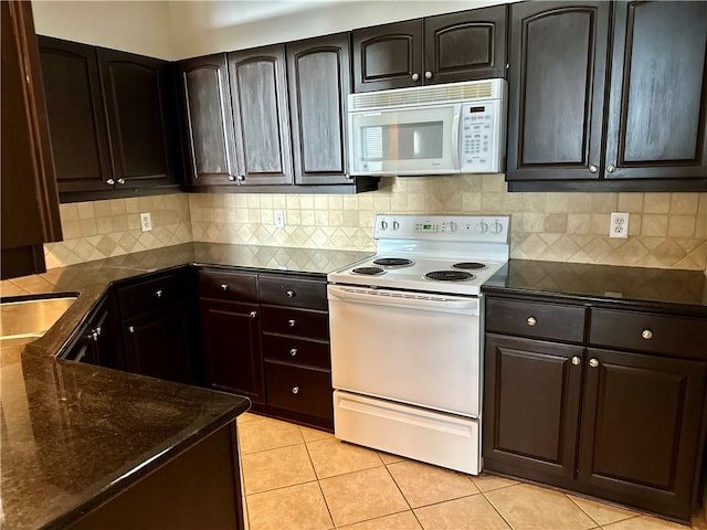 kitchen with dark brown cabinetry, decorative backsplash, white appliances, and light tile patterned floors