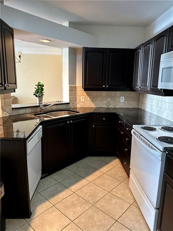 kitchen with decorative backsplash, white appliances, light tile patterned flooring, and sink