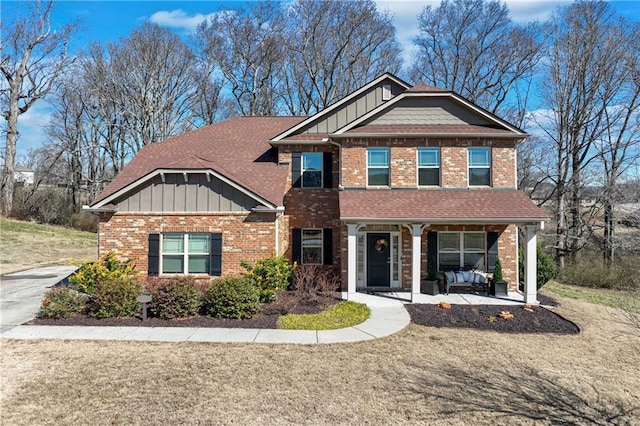 craftsman-style home with a porch, brick siding, a shingled roof, and board and batten siding