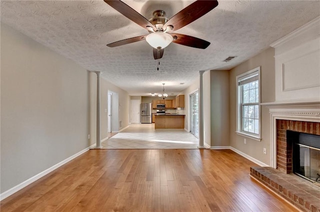 5229 Pine Branch Ct, Sugar Hill, GA 30518 - unfurnished living room with a brick fireplace, baseboards, light wood-style flooring, a ceiling fan, and a textured ceiling