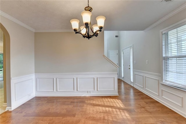 5229 Pine Branch Ct, Sugar Hill, GA 30518 - unfurnished dining area featuring arched walkways, light wood-style flooring, a chandelier, crown molding, and wainscoting