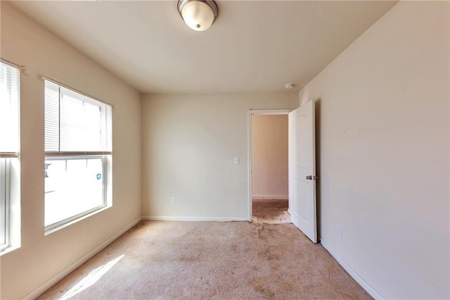 unfurnished room featuring baseboards and light colored carpet