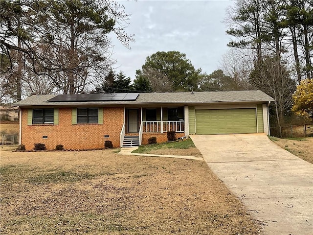 ranch-style house with a garage, a porch, a front lawn, and solar panels