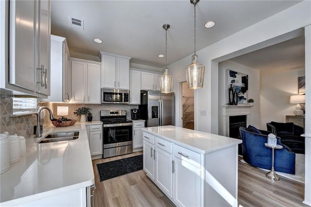 kitchen featuring white cabinetry, a center island, stainless steel appliances, and sink