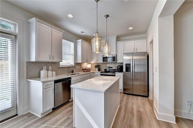 kitchen featuring sink, stainless steel appliances, a center island, and plenty of natural light