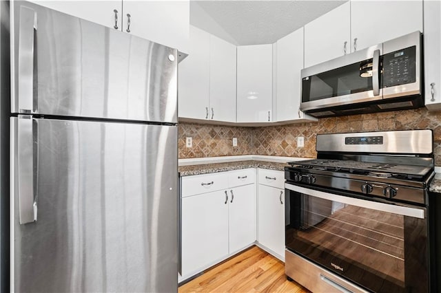 kitchen featuring decorative backsplash, white cabinetry, stainless steel appliances, and light wood-type flooring