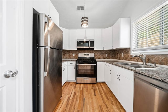 kitchen with visible vents, light wood-type flooring, decorative backsplash, appliances with stainless steel finishes, and a sink