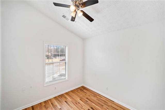 unfurnished room with baseboards, ceiling fan, lofted ceiling, light wood-style flooring, and a textured ceiling