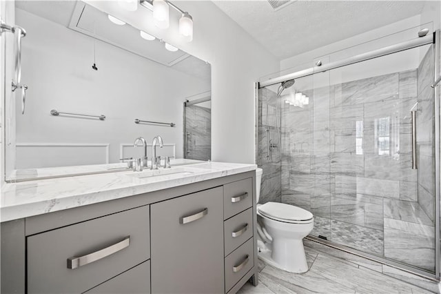 full bath with toilet, a stall shower, vanity, and a textured ceiling