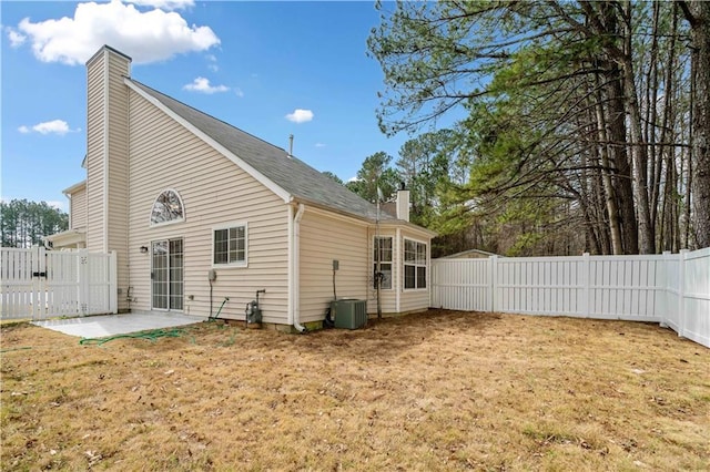 rear view of property with a yard, a patio, a fenced backyard, and a chimney