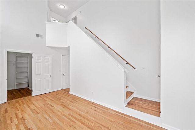 stairs with visible vents, baseboards, wood finished floors, and a towering ceiling