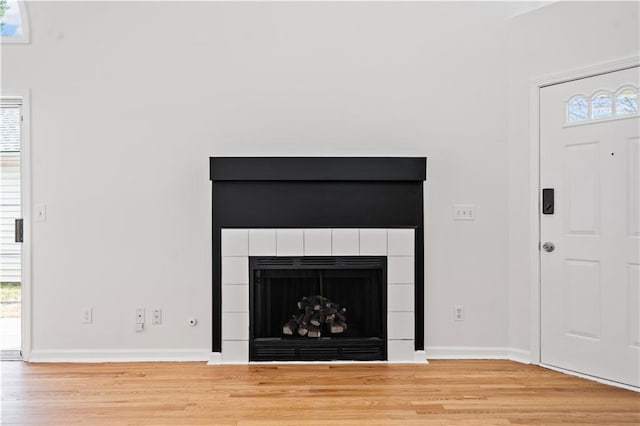 interior details featuring baseboards, wood finished floors, and a tiled fireplace