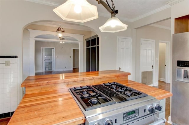 kitchen featuring ornamental molding, appliances with stainless steel finishes, wood counters, and decorative light fixtures