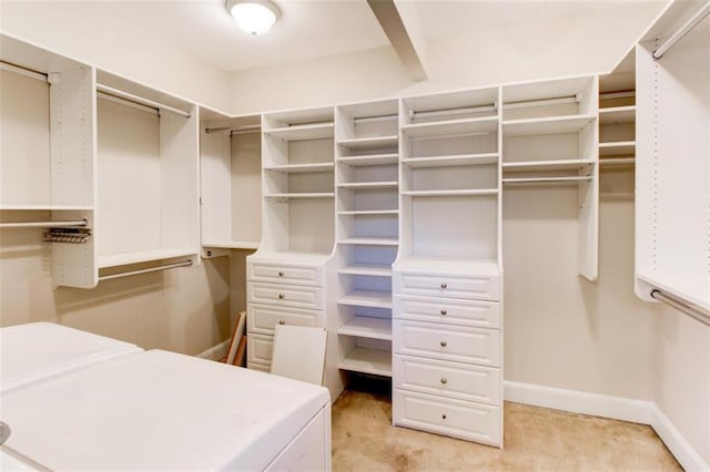 walk in closet with light carpet and washer and dryer