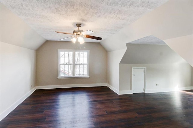 additional living space featuring ceiling fan, lofted ceiling, dark wood-type flooring, and a textured ceiling