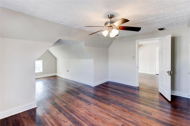 additional living space featuring ceiling fan, lofted ceiling, dark wood-type flooring, and a textured ceiling