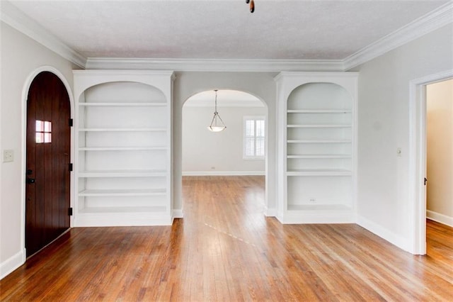 foyer entrance with ornamental molding and wood-type flooring