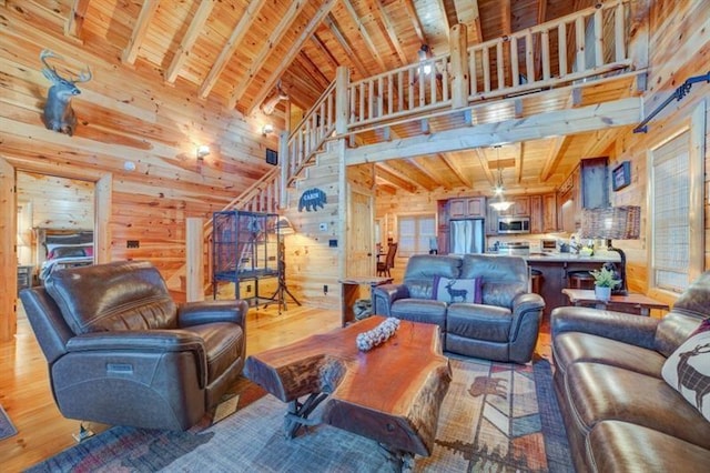 living room with beam ceiling, wooden ceiling, a high ceiling, light hardwood / wood-style floors, and wooden walls