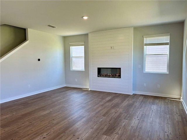 unfurnished living room with a large fireplace and dark hardwood / wood-style flooring