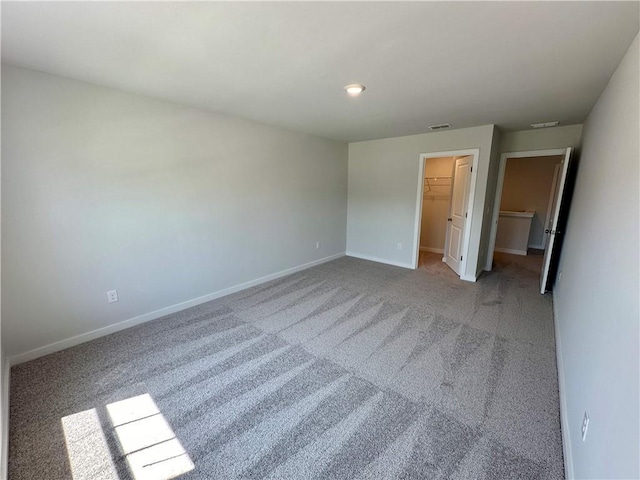 unfurnished bedroom with a walk in closet, a closet, and carpet