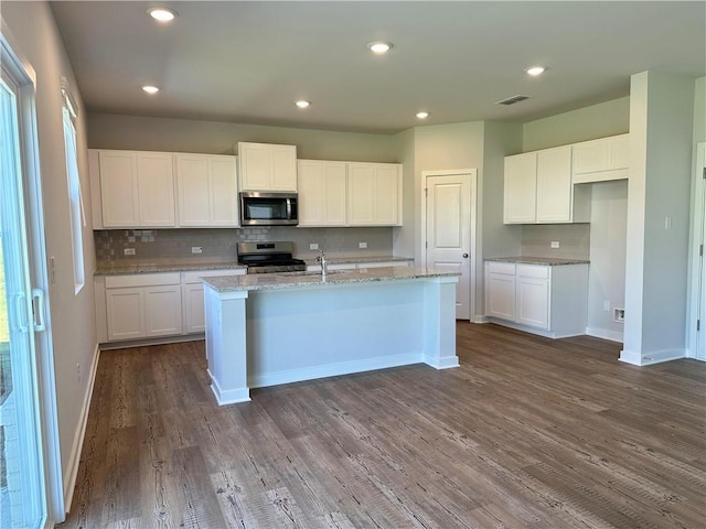 kitchen with white cabinetry, appliances with stainless steel finishes, an island with sink, and light stone counters