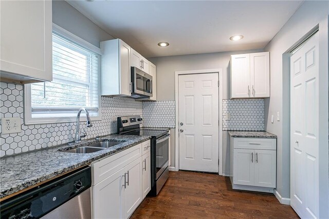 kitchen with light stone counters, sink, white cabinetry, stainless steel appliances, and dark hardwood / wood-style floors