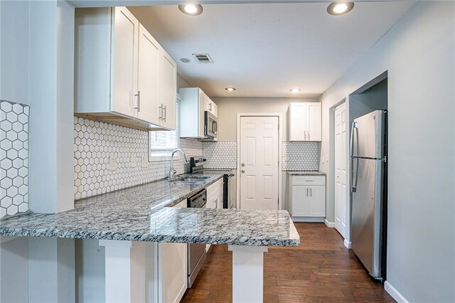 kitchen featuring a kitchen breakfast bar, kitchen peninsula, stainless steel appliances, and white cabinets