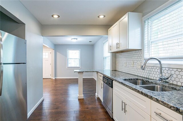 kitchen with white cabinets, sink, dark wood-type flooring, appliances with stainless steel finishes, and light stone countertops