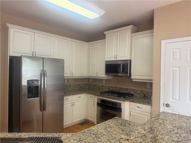 1919 Barrett Knoll Cir NW, Kennesaw, GA 30152 - kitchen with appliances with stainless steel finishes, white cabinetry, decorative backsplash, and dark stone counters