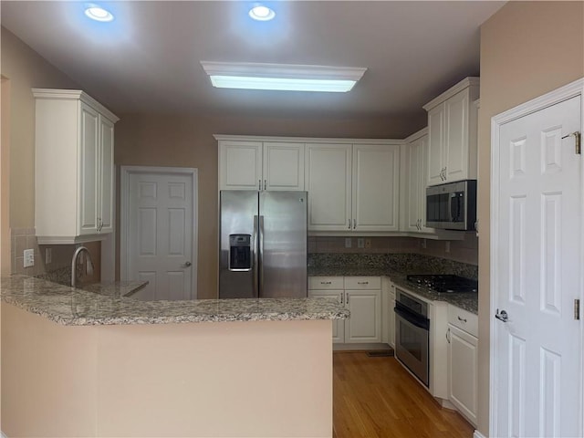 1919 Barrett Knoll Cir NW, Kennesaw, GA 30152 - kitchen with appliances with stainless steel finishes, a peninsula, light wood-type flooring, light stone countertops, and recessed lighting