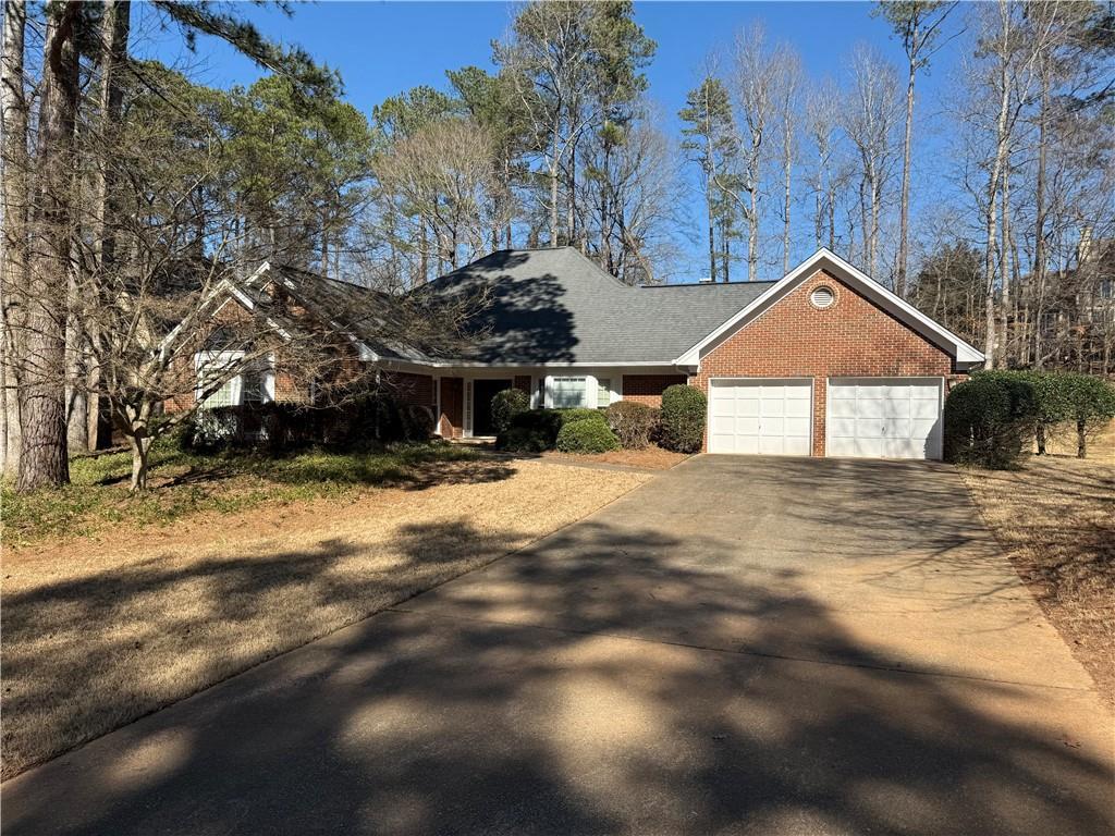 single story home with concrete driveway, brick siding, and an attached garage