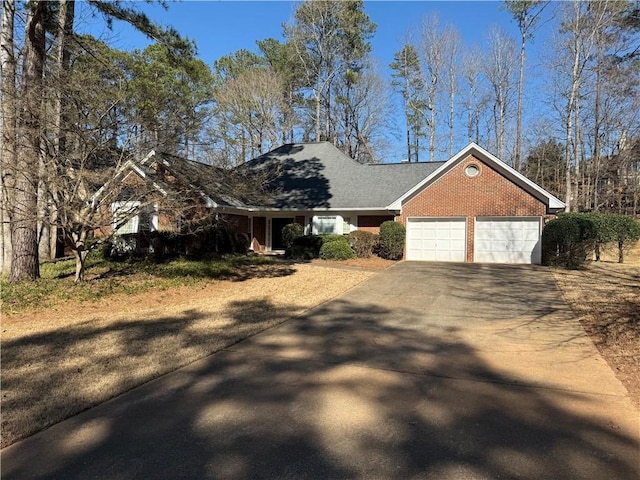 single story home with concrete driveway, brick siding, and an attached garage