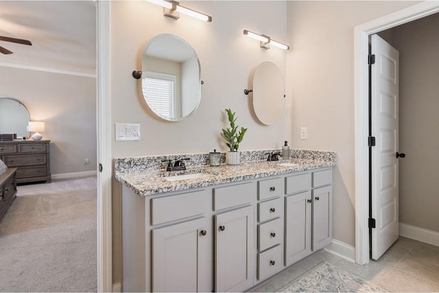 full bath with double vanity, baseboards, a ceiling fan, and a sink