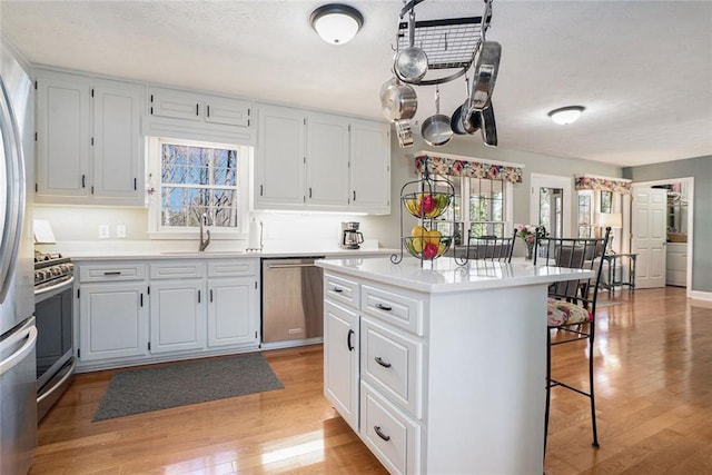 kitchen with stainless steel appliances, a breakfast bar area, light wood-type flooring, and a sink