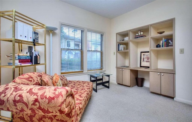 living area with carpet floors, built in desk, and baseboards