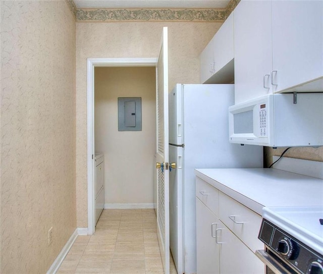 kitchen with white microwave, stove, white cabinetry, light countertops, and electric panel