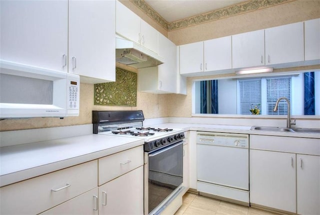 kitchen featuring white appliances, under cabinet range hood, light countertops, and a sink