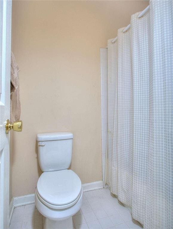 full bathroom featuring a shower with curtain, tile patterned flooring, toilet, and baseboards