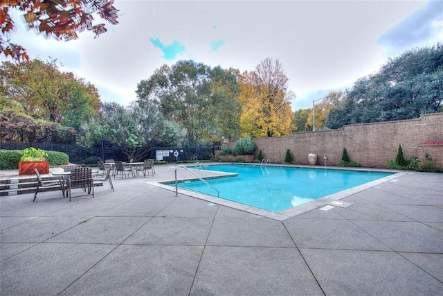 community pool with a patio and fence