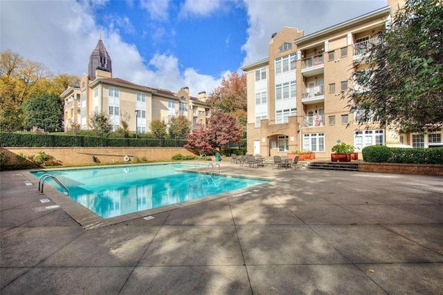 pool with a patio area and fence