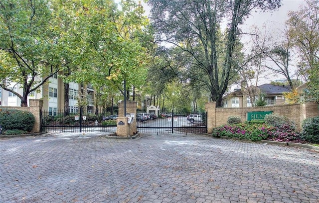 view of road with a gate, a gated entry, and curbs