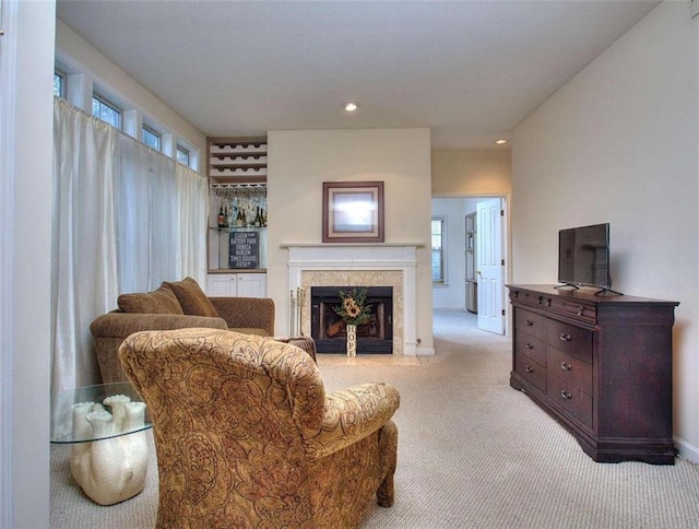 living room featuring recessed lighting, a fireplace with flush hearth, baseboards, and light colored carpet