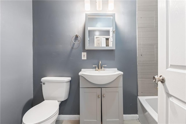 bathroom featuring vanity, tiled tub, and toilet