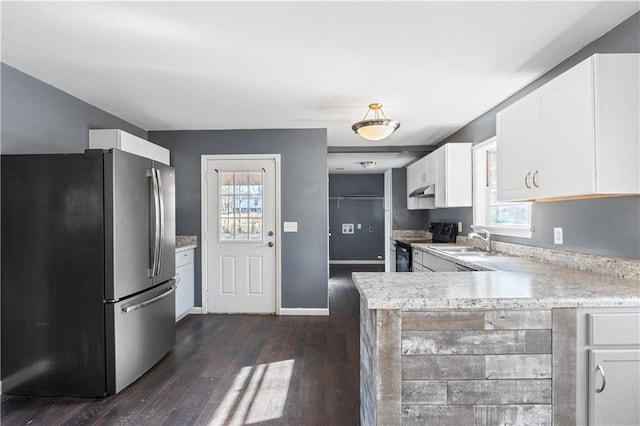 kitchen featuring black electric range oven, sink, stainless steel refrigerator, white cabinetry, and kitchen peninsula