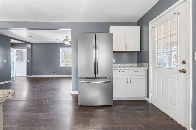 kitchen featuring white cabinetry, dark hardwood / wood-style floors, stainless steel fridge, ceiling fan, and light stone countertops