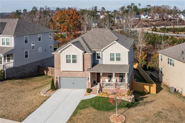 view of front of house featuring covered porch, central AC, a garage, and a front yard